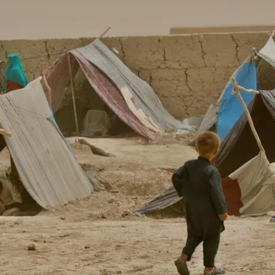 A woman and child walk between the makeshift tents in Nawabad Farabi-ha camp for internally displaced people in Mazar-e Sharif in northern Afghanistan.